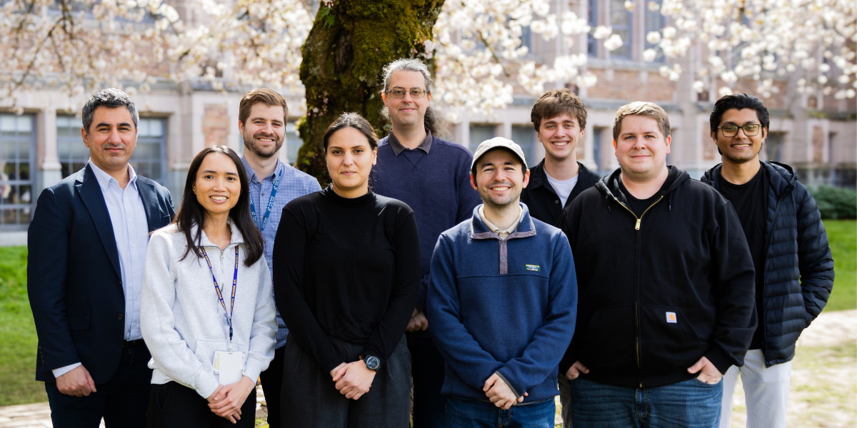 SAIL Lab team members pose at the Quad in front of cherry blossoms.